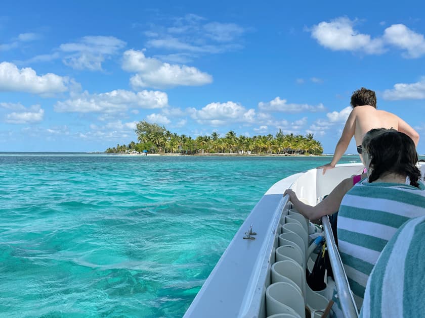 A boat is approaching a tropical island with lush greenery under a clear blue sky. A boat is approaching a tropical island with lush greenery under a clear blue sky.