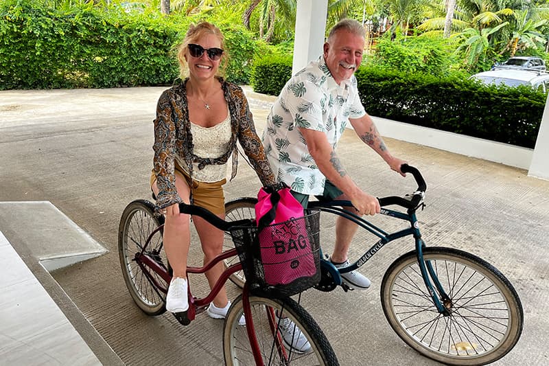 A woman and a man are joyfully riding side-by-side on bicycles in a tropical setting. A woman and a man are joyfully riding side-by-side on bicycles in a tropical setting.