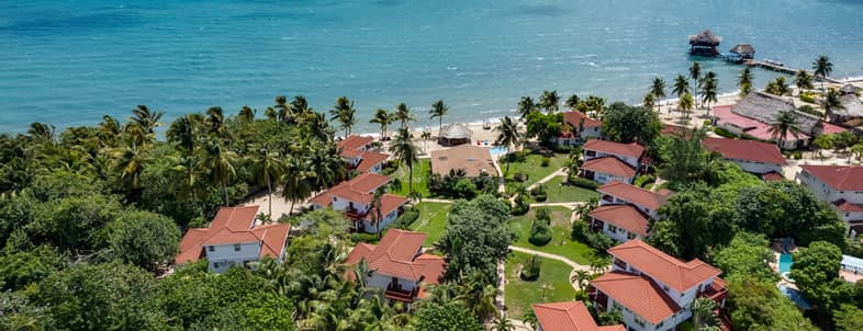 Aerial view of a tropical beach resort surrounded by palm trees and clear blue water. Aerial view of a tropical beach resort surrounded by palm trees and clear blue water.