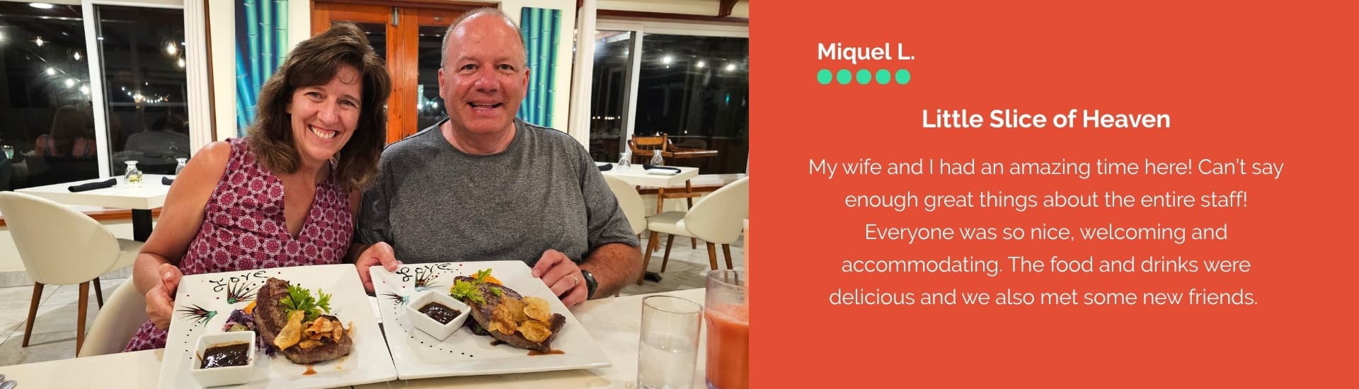 A smiling couple sits at a dining table with plates of food in front of them.