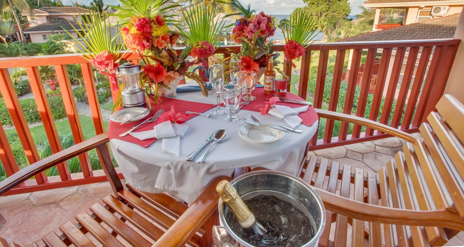 Table set for two with tropical flowers on balcony overlooking the grounds of the property. With a bottle of champagne.