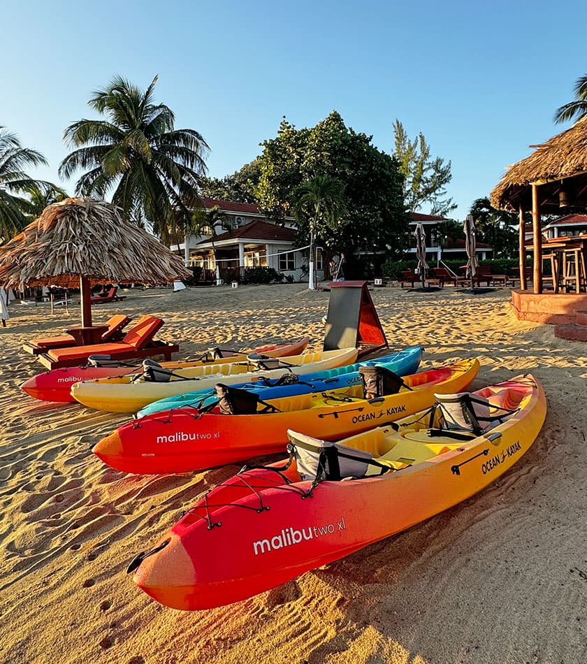 Colorful kayaks lined up on the sandy beach under a clear blue sky.