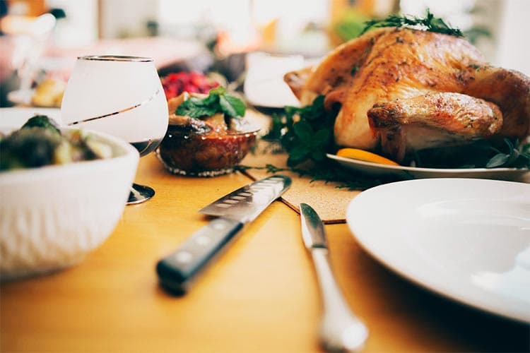 A beautifully set dining table featuring a roasted turkey, side dishes, and wine glasses.