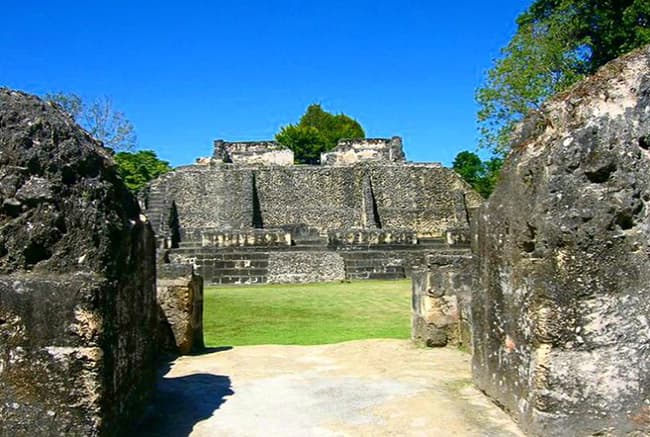 Ancient stone ruins of a temple structure under a clear blue sky, framed by stone walls.