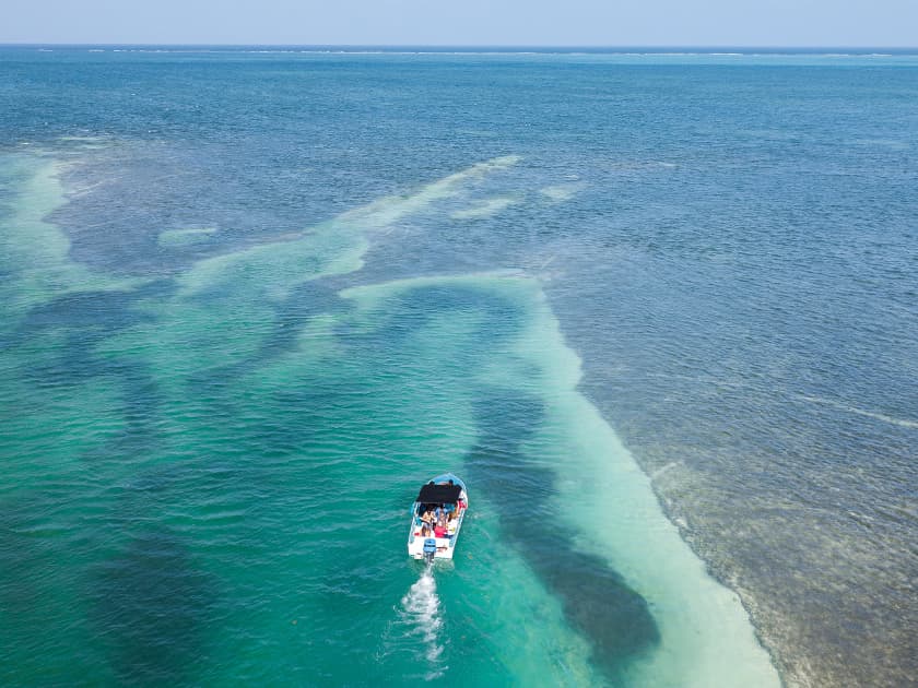A boat navigates through clear turquoise waters.
