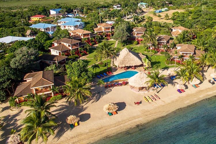 Aerial view of a tropical resort with beaches, palm trees, and a swimming pool.