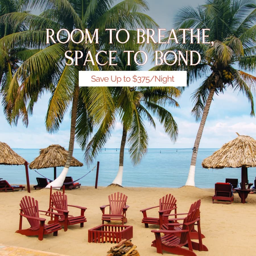 Chairs arranged around bonfire wood on the beach at Belizean Dreams Resort.