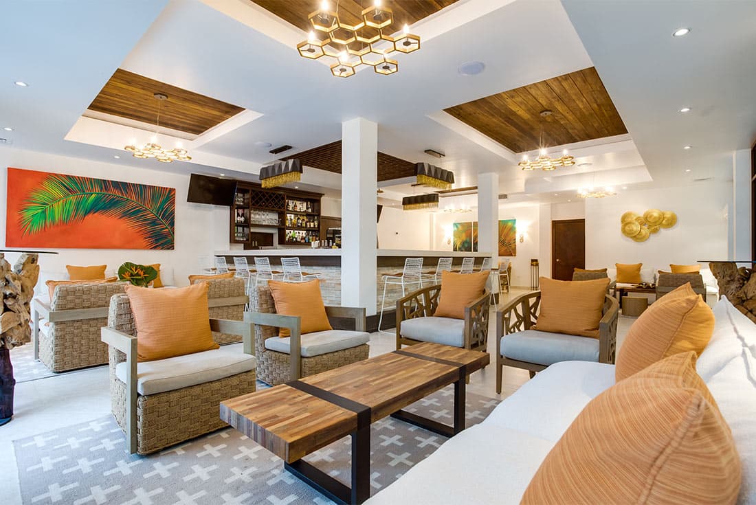 A modern and stylish hotel lobby with a bar area, comfortable seating, and a large abstract painting. The overall atmosphere is warm and inviting.