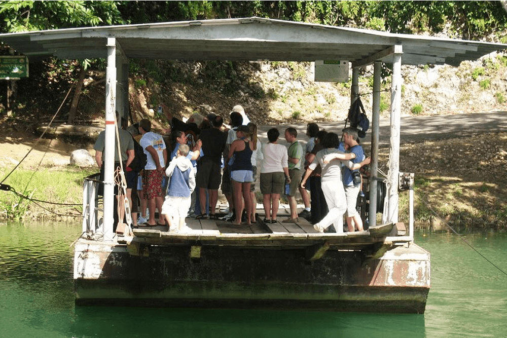 Large group of people on boat anchored on shore.