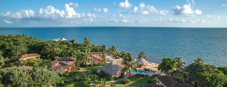 Aerial view of a beachfront resort surrounded by lush greenery and calm blue waters. Aerial view of a beachfront resort surrounded by lush greenery and calm blue waters.