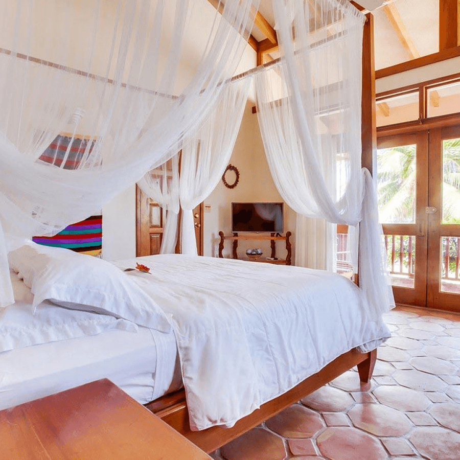 A bedroom with a four-poster bed and a mosquito net.