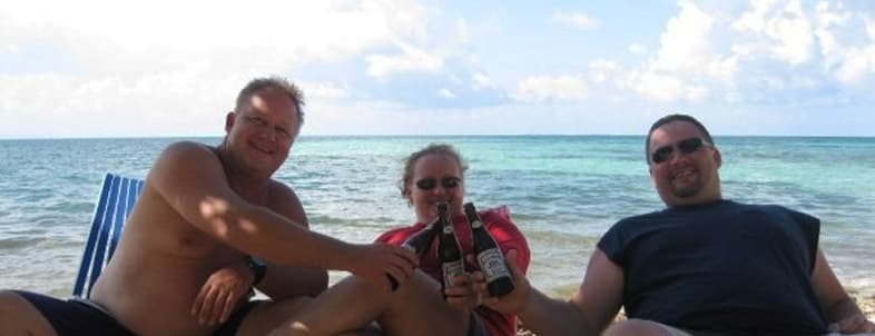 Three people sitting on a beach, enjoying drinks with the ocean in the background. Three people sitting on a beach, enjoying drinks with the ocean in the background.