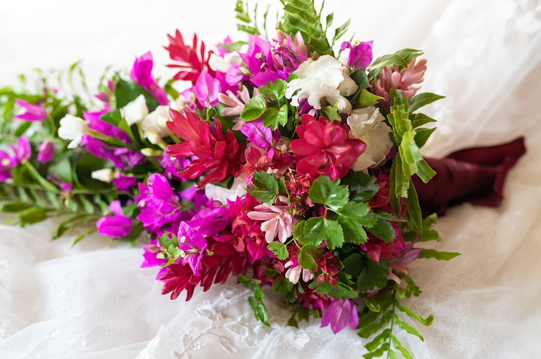 Vibrant wedding bouquet with pink and red flowers, including bougainvillea and ginger lilies