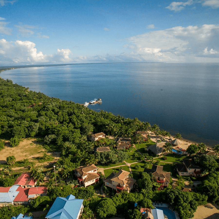 An aerial view of a coastal resort with a beach, buildings, and a pier.
