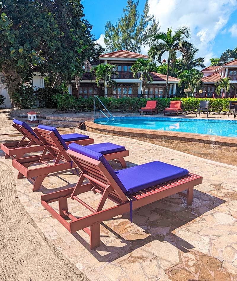 Poolside loungers with purple cushions under a clear blue sky.
