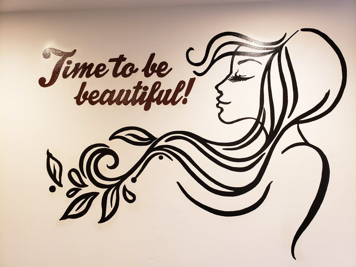 A black and white wall decal of a woman with flowing hair and the text "Time to be beautiful!"