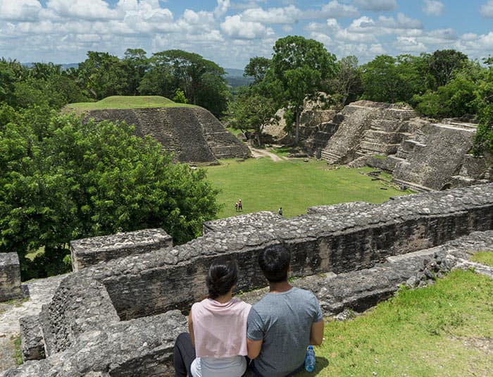 Couple sitting among stone Mayan ruins