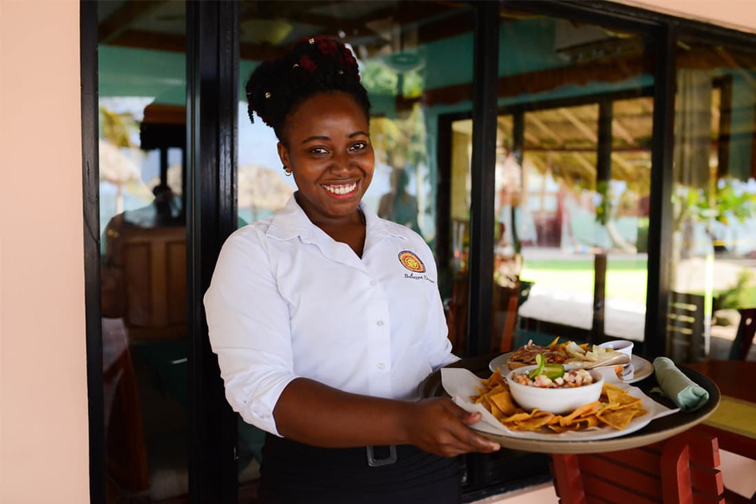 A smiling server stands with a serving plate.