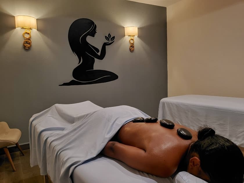A woman receives a massage with hot stones in a serene spa setting.