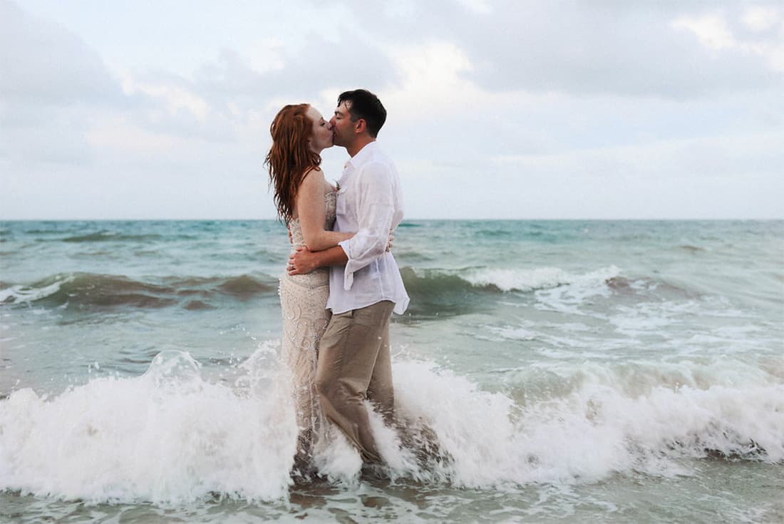 A beautiful young couple kiss passionately on the beach.