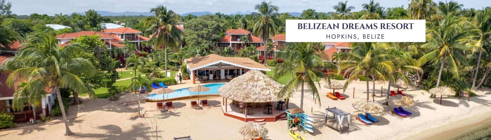 Aerial view of the Belizean Dreams Resort, featuring lush greenery, sandy beach, and a swimming pool.