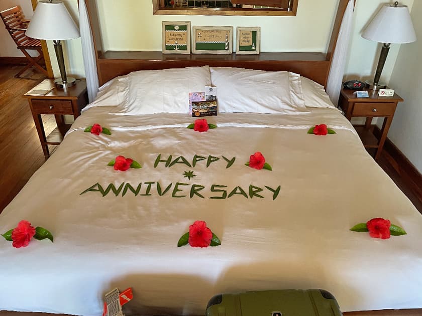 A decorated bed with "HAPPY ANNIVERSARY" written in leaves and flowers. A decorated bed with "HAPPY ANNIVERSARY" written in leaves and flowers.