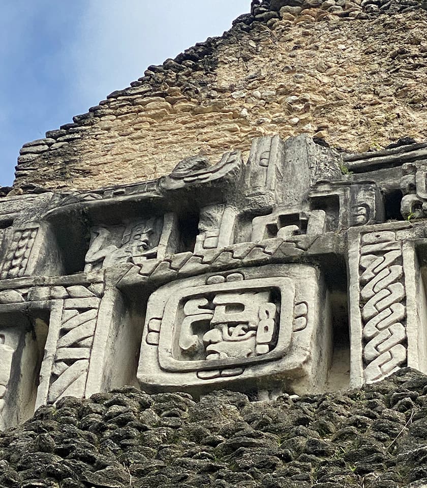 Ancient Mayan stone carvings adorn the weathered wall of a temple.