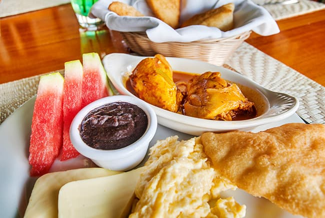 A plate of food featuring watermelon, black bean dip, shredded chicken, cheese, and a fried pastry.