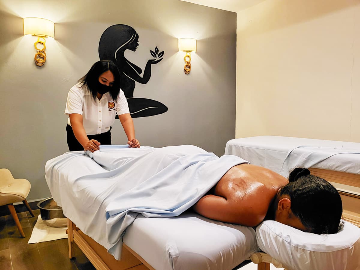 A female guest receives a hot stone massage from a female massage therapist.