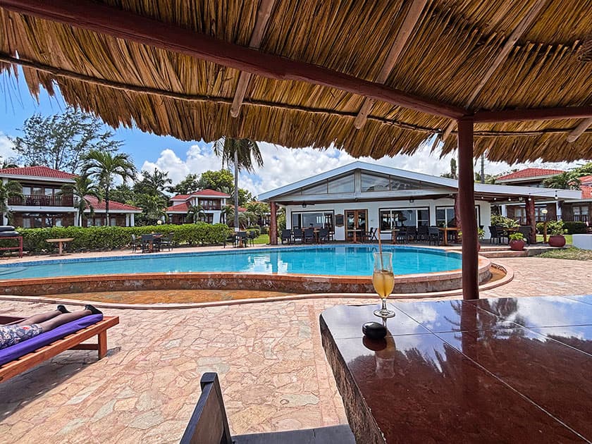 A tranquil poolside view featuring a drink on a table and resort buildings in the background. A tranquil poolside view featuring a drink on a table and resort buildings in the background.