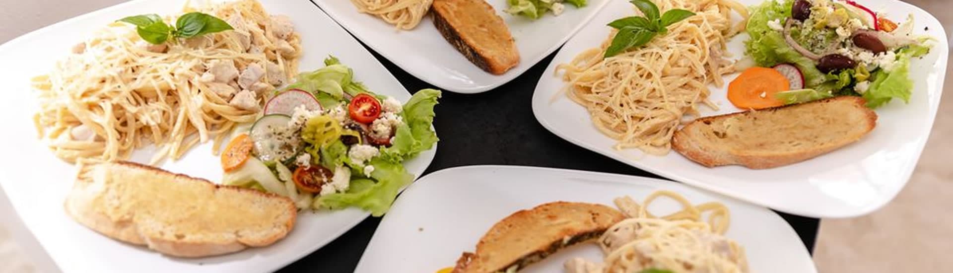 Plates of pasta with chicken and salad