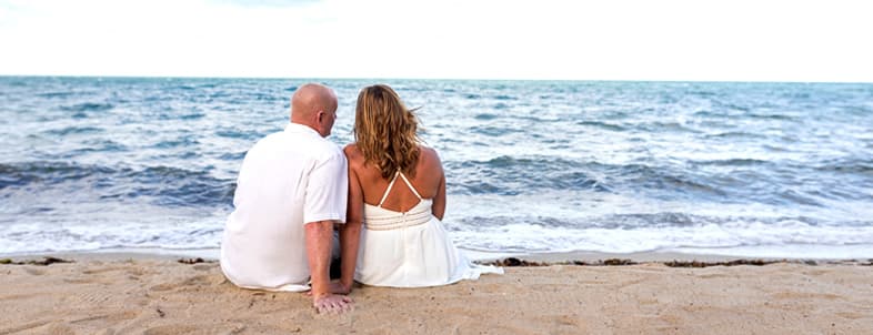 A couple sits close together on the beach, gazing at the ocean. A couple sits close together on the beach, gazing at the ocean.