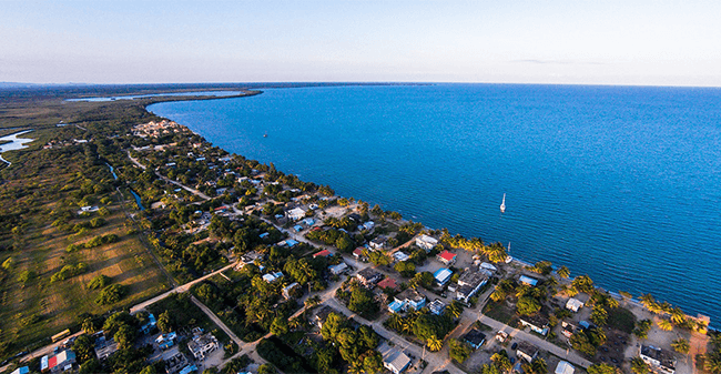 Aerial view of a coastal village with homes near a calm blue sea.