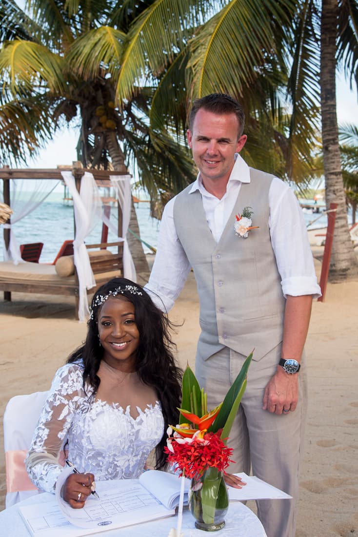 Beautiful young couple in wedding clothes signs their marriage license on the beach.