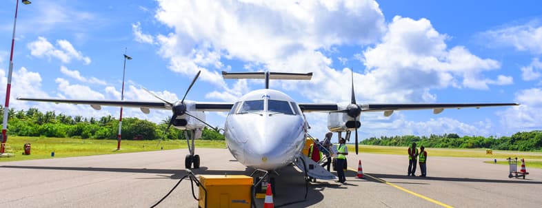 A small airplane is parked on a runway with ground crew members preparing for departure.