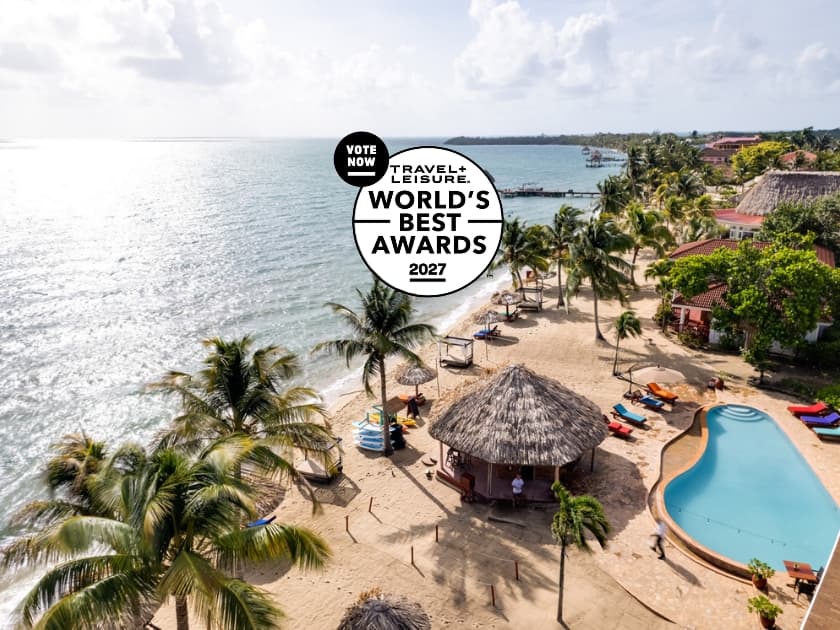 A scenic beach with palm trees, a pool, and resort amenities, featuring a promotional banner for the 2027 World's Best Awards by Travel + Leisure. A scenic beach with palm trees, a pool, and resort amenities, featuring a promotional banner for the 2027 World's Best Awards by Travel + Leisure.