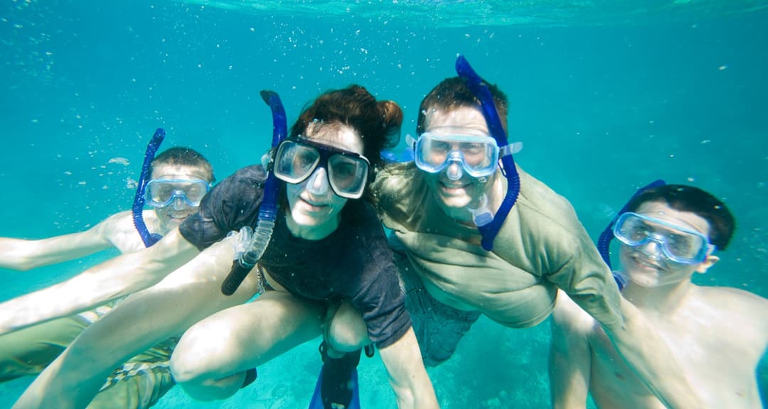 Adults and children snorkeling together in Belize