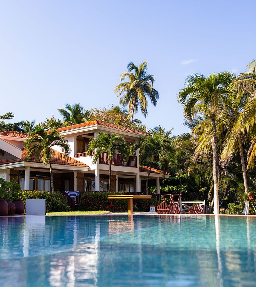 A luxurious villa surrounded by palm trees and a serene pool.