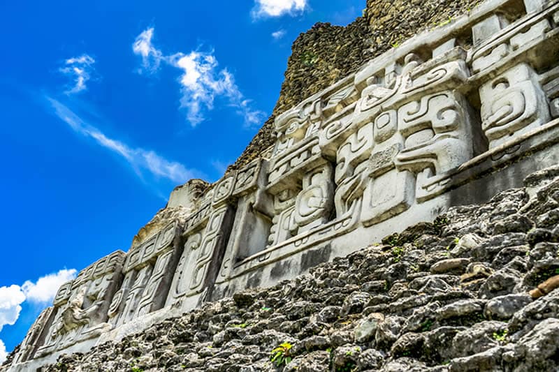 Ancient stone carvings on a temple facade rising against a blue sky. Ancient stone carvings on a temple facade rising against a blue sky.