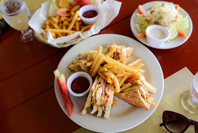 A plate of chicken sandwiches with fries and dipping sauce, accompanied by a side salad and watermelon.
