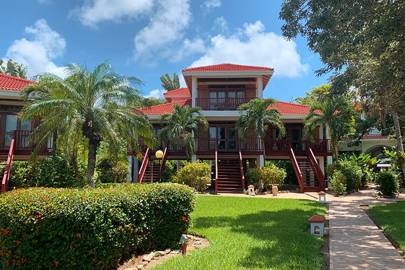 A tropical building with red roofs surrounded by palm trees and green landscaping. A tropical building with red roofs surrounded by palm trees and green landscaping.