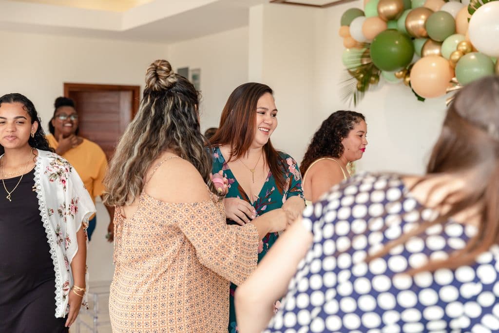 Several smiling ladies gather around to celebrate a baby shower.