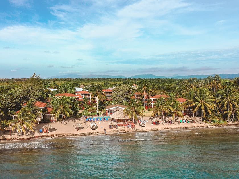 Aerial view of Belize beach resort with palm trees, oceanfront villas, and sandy shoreline. Aerial view of Belize beach resort with palm trees, oceanfront villas, and sandy shoreline.